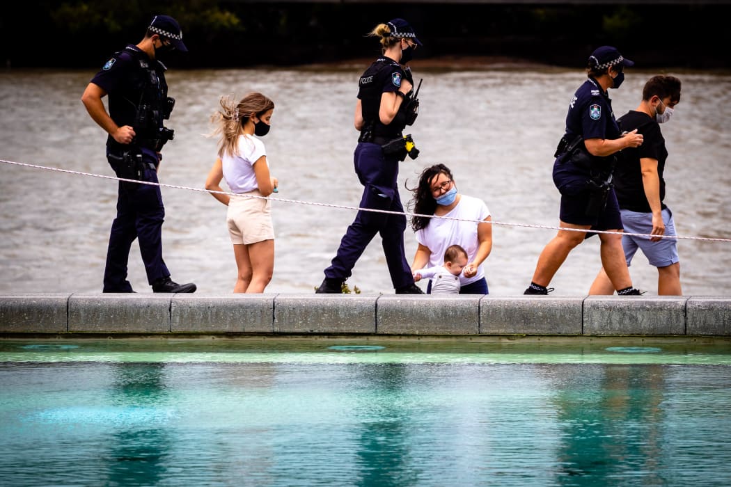 Police patrol past mask-clad people on the deserted South Bank beach on the first day of a snap lockdown in Brisbane on January 9, 2021