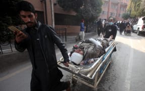 People push a stretcher carrying an injured victim after a mosque blast inside the police headquarters, at a hospital in Peshawar on January 30, 2023. - A blast at a mosque inside a police headquarters in Pakistan on January 30 killed at least 25 worshippers and wounded 120 more, officials said. (Photo by Zafar IQBAL / AFP)