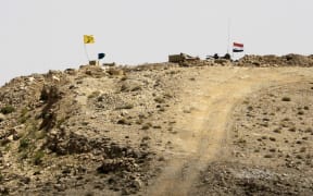 A picture taken in August during a tour guided by the Lebanese Shiite Hezbollah movement shows the flags of the movement and the Syrian government (R) flying over a position held by the Syrian government forces near the border with Lebanon.
