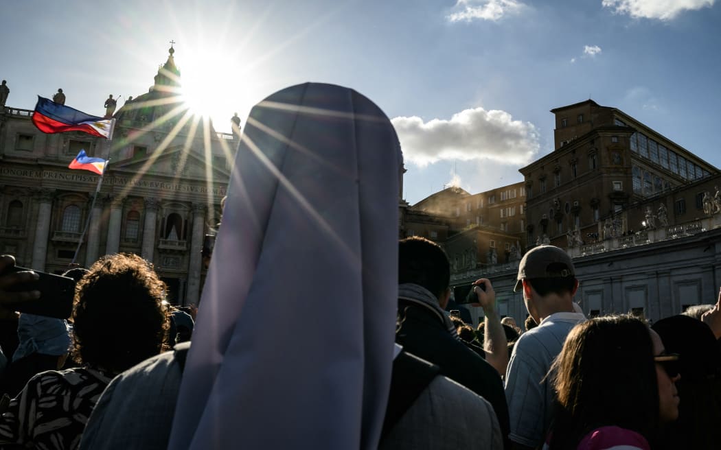 People gather  at Saint Peter's Square after white smoke rose from the chimney of the Sistine Chapel signalling that cardinals elected a new pope during their secret conclave, in The Vatican, on May 8, 2025. (Photo by JEFF PACHOUD / AFP)