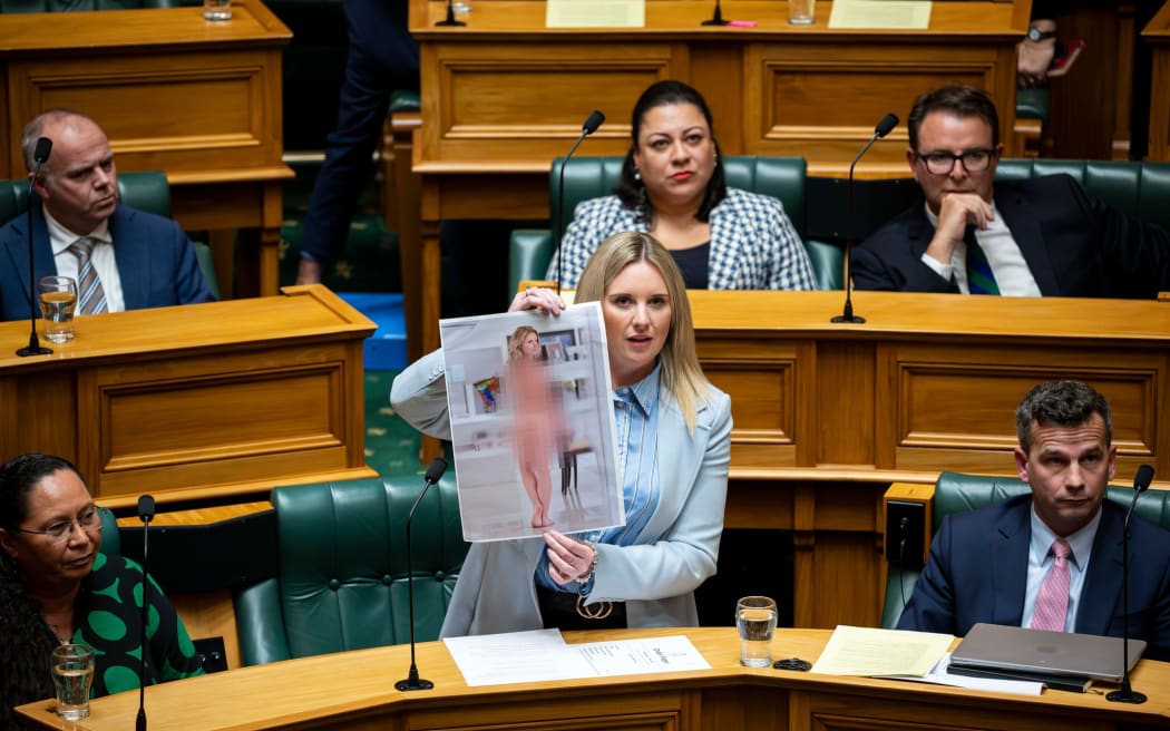 ACT MP Laura McClure holds up a faked nude photo of herself that she created when discussing the Deepfake Digital Harm and Exploitation Bill.