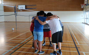 Four teenagers in sports huddle in gym
