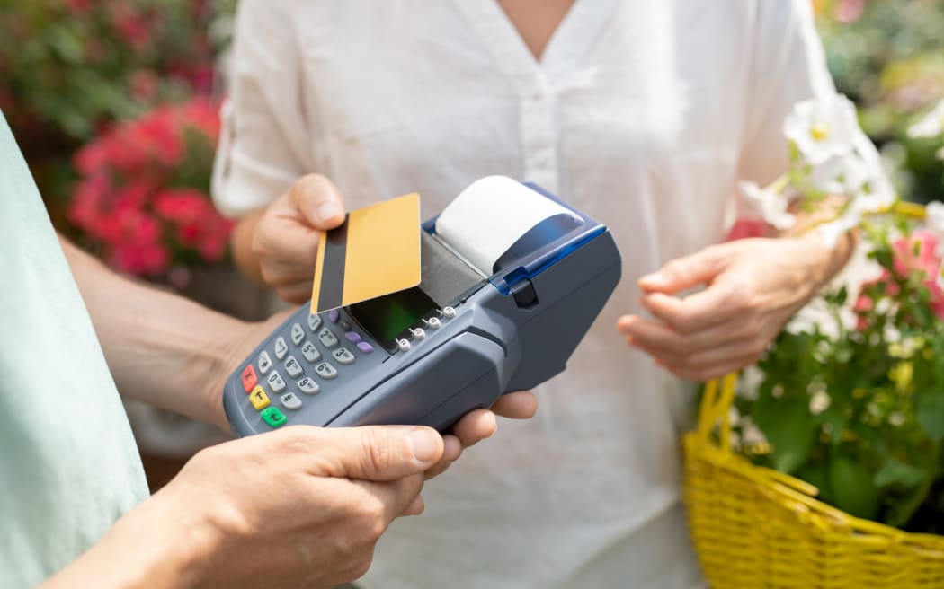 Contemporary female buyer using credit card to pay for some fresh potted flowers in contemporary garden center