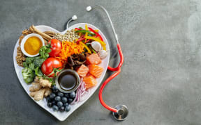 Fresh food for a healthy heart with acai, lentils, soy sauce, ginger, salmon, carrot, tomato, turmeric, cinnamon, walnuts, garlic, peppers, broccoli, basil, onion with a stethoscope and copy space