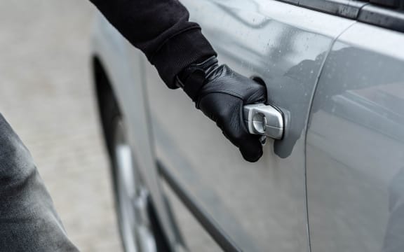 Close up on car thief hand pulling the handle of a car. Car thief, car theft concept