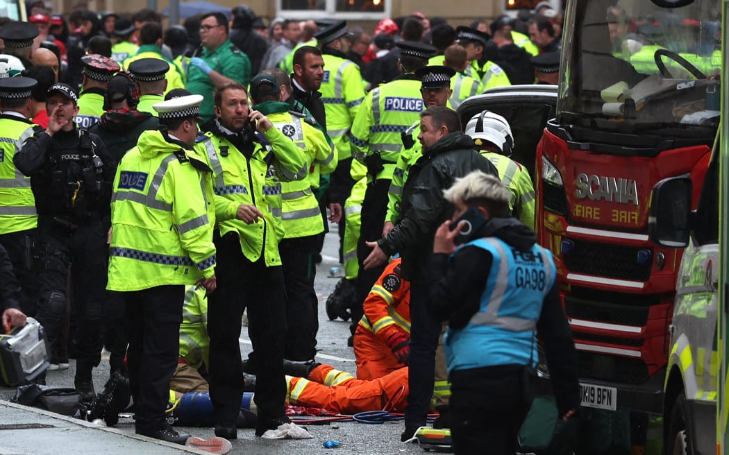 Members of the emergency services treat members of the public inside a Police cordon at the scene of an incident, on the sidelines of an open-top bus victory parade for Liverpool's Premier League title win.