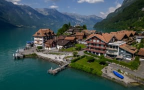 A picture taken on June 2, 2023 shows the village of Iseltwald at the shore of Lake Brienz, in the Swiss Alps. Ever since a hugely popular South Korean series on Netflix featured a romantic scene in this very spot, the picturesque lakeside village of Iseltwald, with a population of around 400 people, has found itself overrun by tourists. They are fans of "Crash Landing on You", which tells the surreal and unlikely story of a South Korean billionaire heiress who accidentally paraglides into the peninsula's demilitarised zone, crashing into a chivalrous army officer serving North Korean leader Kim Jong Un. (Photo by Fabrice COFFRINI / AFP)