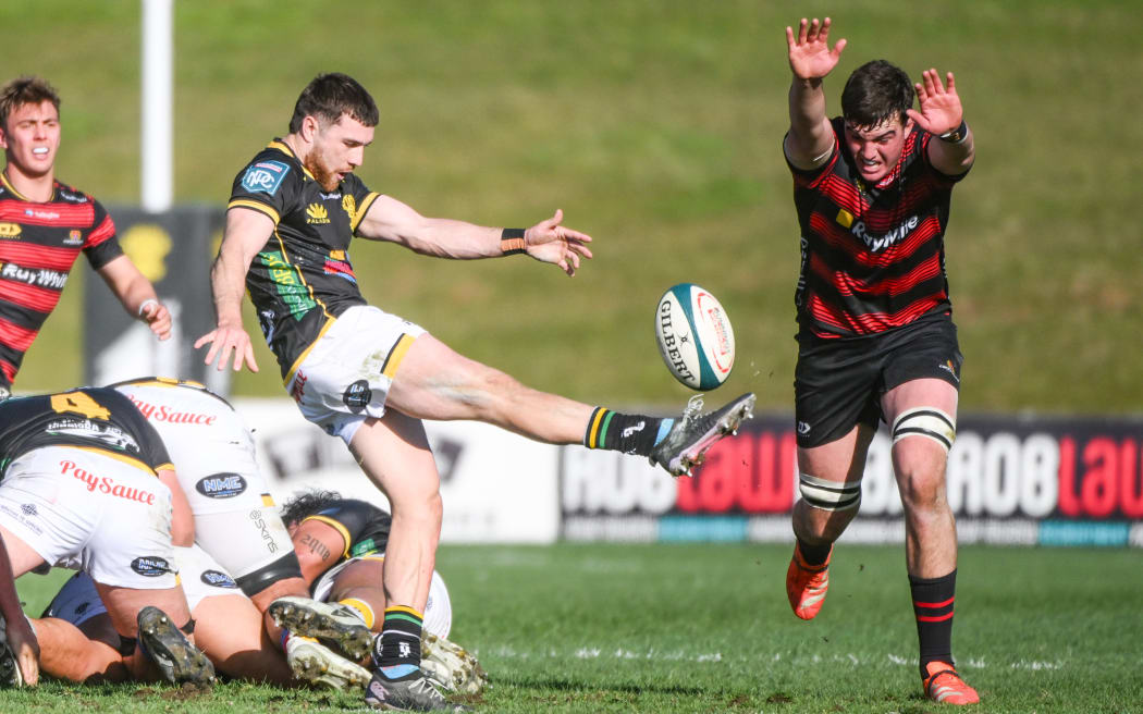 Kyle Preston of Wellington kicks as Jamie Hannah of Canterbury attempts to block.