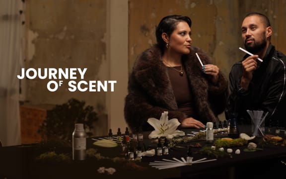 Whitney Steel & Nathan Taare sit at a table and smell samples of a perfume. White text on the left reads: "JOURNEY OF SCENT."
