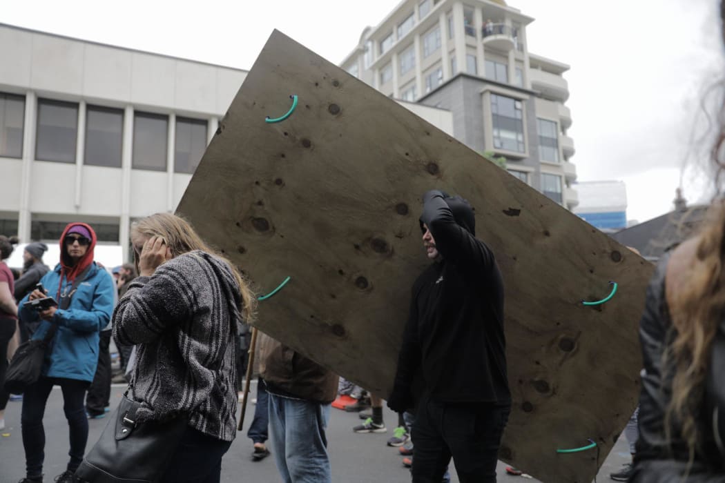 Protesters carry a wooden shield in the crowd.
