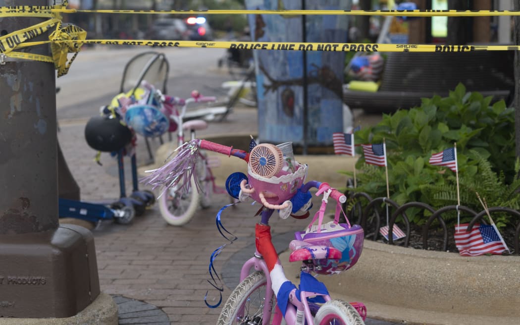 Police crime tape around abandoned children's bicycles and baby strollers at the scene of the Fourth of July parade shooting in Highland Park, Illinois.