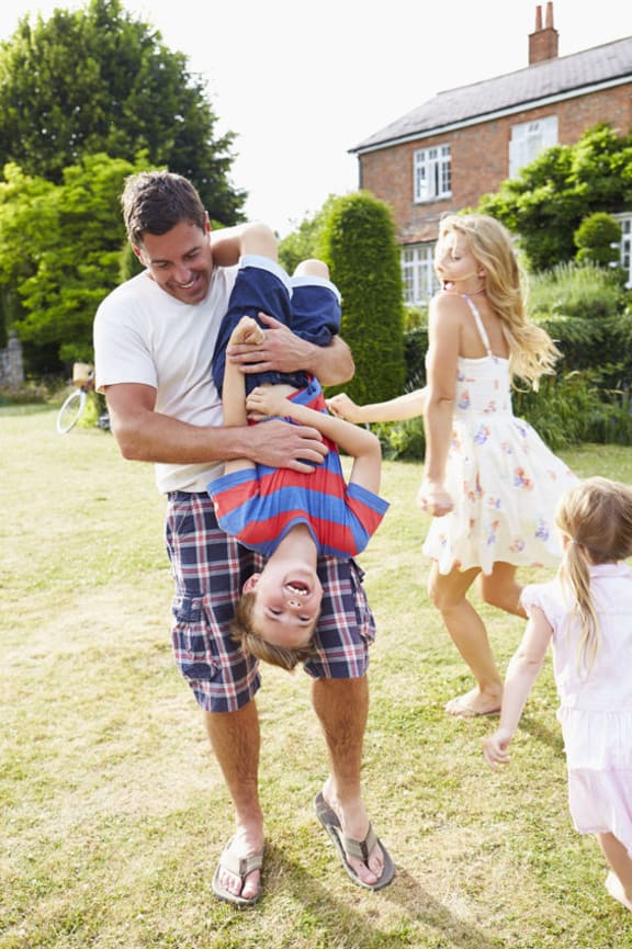 A photo of  a father hanging his son upside down whilst playing