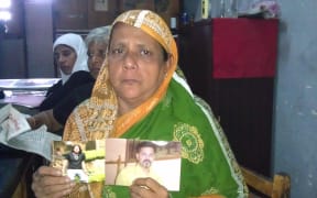 A Sri Lankan woman holds pictures of her missing son.