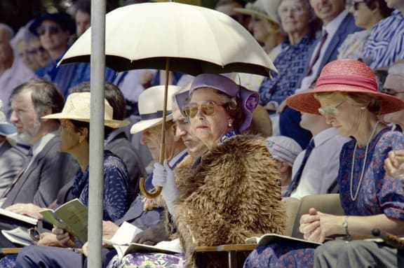 British Queen Elizabeth II (C), shielding herself from the sun with an umbrella, listen to a speech by Anglican Archbishop Hui Vercoe during the celebrations of New Zealand's 150th anniversary in Waitangi on February 6, 1990.
