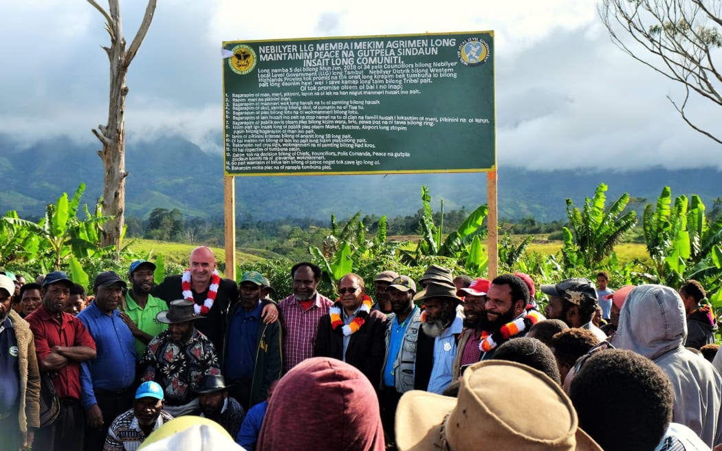 Councilors lining up with PNG's Western Highlands Provincial Administrator, Joseph Neng and ICRC Mt Hagen Head of Office, Kakhaber Khasaia, in front of the sign with the 15 tribal rules on it.