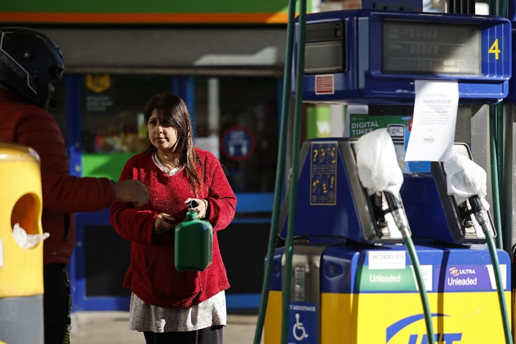 A woman holds a petrol can as a motorcyclist speaks to her at partly taped-off petrol and diesel pumps at a petrol station in Leyton, east London on September 29, 2021.