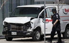 Police inspect a van which mounted the pavement and hit a crowd of pedestrians in Toronto.