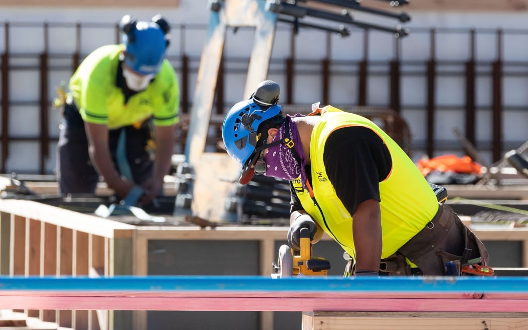 Masked construction workers are pictured at a building site on the first day of the easing of restrictions in Wellington on April 28, 2020, following the COVID-19 coronavirus outbreak. -