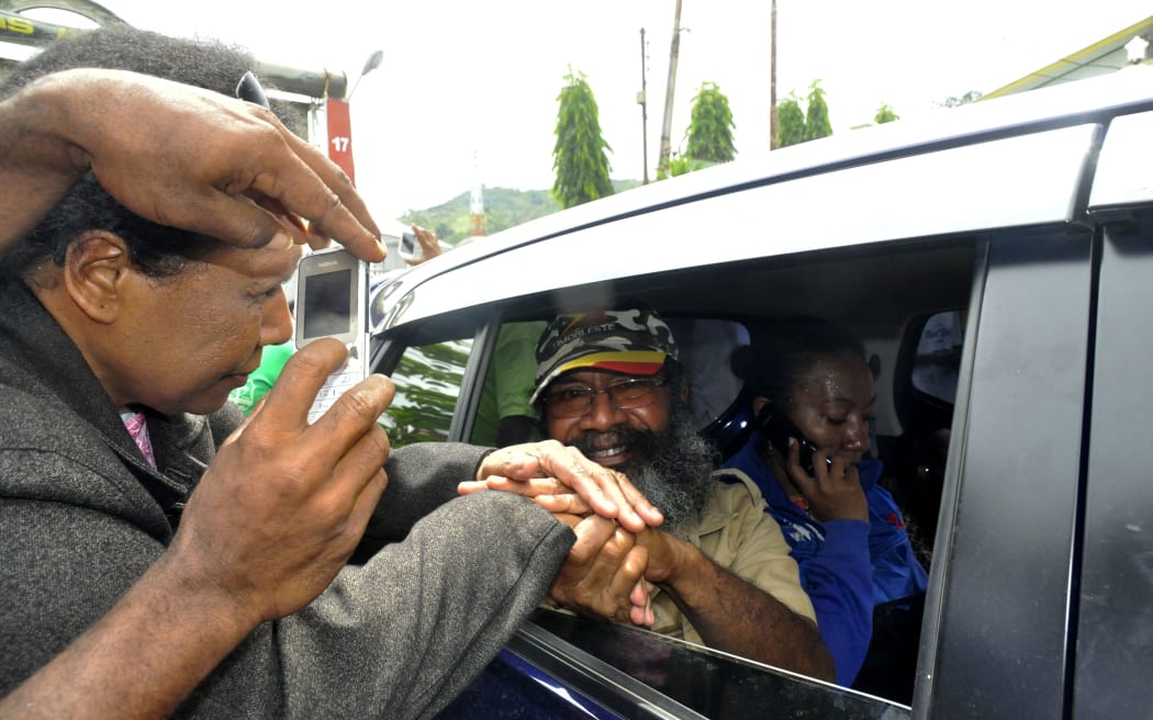 Papuan pro-independence activist Filep Karma (inside vehicle) shakes hands with his supporters after being released from prison in Abepura, Papua province, on November 19, 2015.