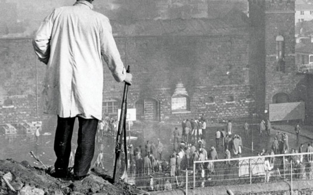 An armed offenders’ squad officer watches the riot.