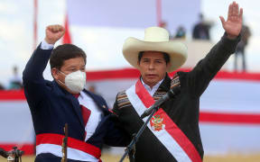 This handout picture released by the Peruvian presidency shows Peru's new Prime Minister Guido Bellido (R) and Peruvian President Pedro Castillo greeting their supporters during the symbolic presidential investiture ceremony at Pampa de la Quinua in Ayacucho, southern Peru, on July 29, 2021.