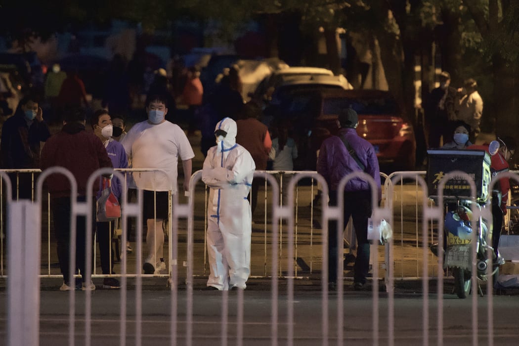 Residents stand next to a barrier inside at a residential area under lockdown to curb the spread of the Covid-19 coronavirus in Panjiayuan, Chaoyang district, in Beijing on April 27, 2022