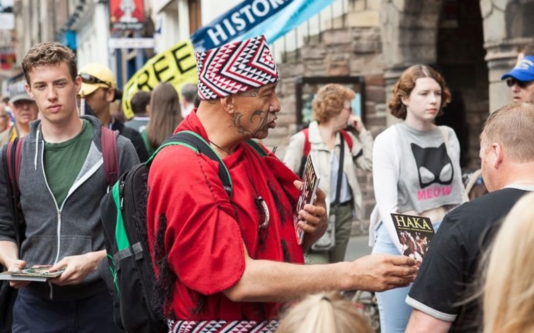 A Haka performer hands out flyers on Edinburgh's Royal Mile.