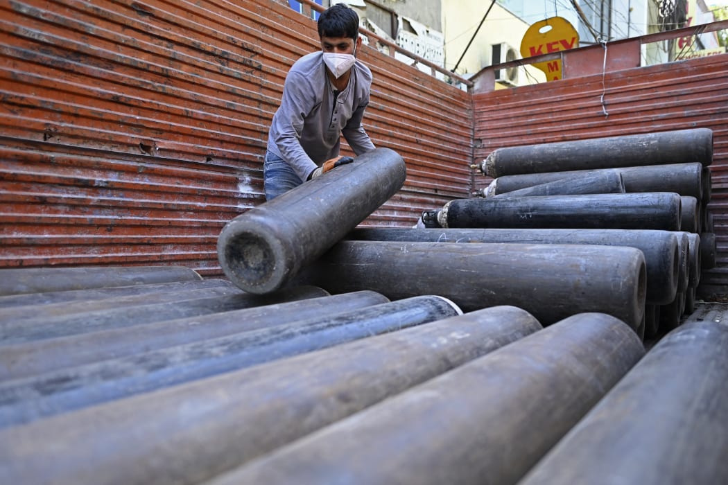 A worker of a wholesale supplier unloads medical oxygen cylinders from a truck that are to be transported to hospitals amid Covid-19 coronavirus pandemic in New Delhi on April 24, 2021.