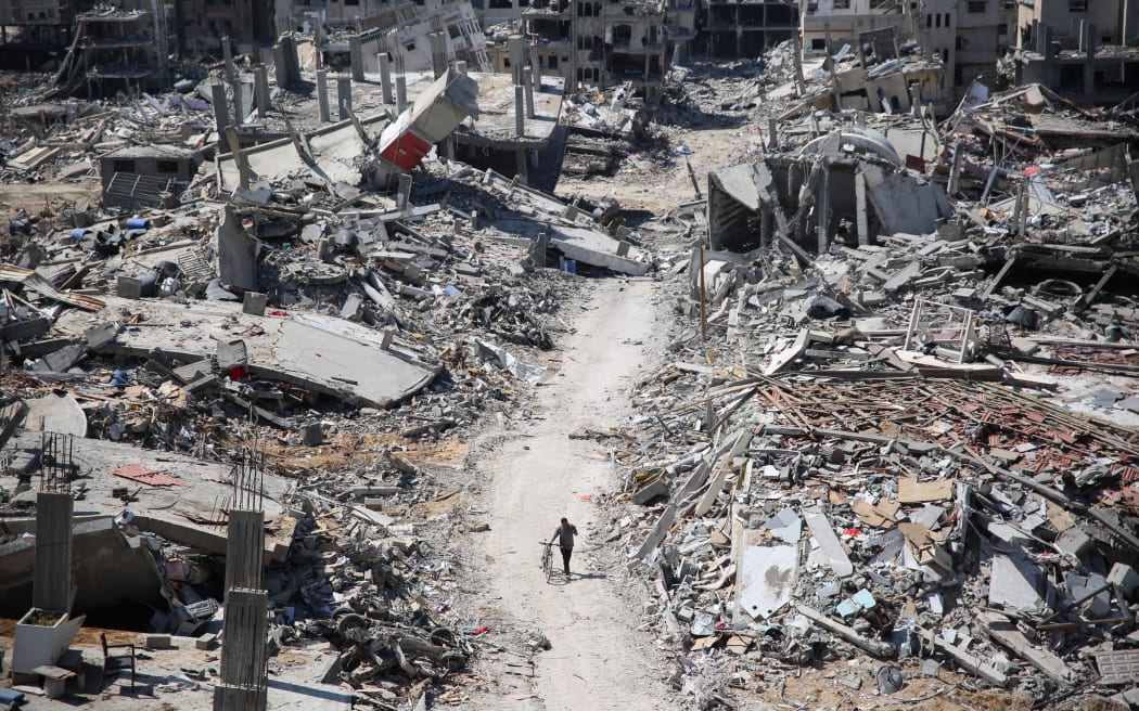 A man pushes a bycicle along as he walks amid building rubble in the devastated area around Gaza's Al-Shifa hospital on April 3, 2024, amid the ongoing conflict between Israel and the Palestinian Hamas militant group. (Photo by AFP)