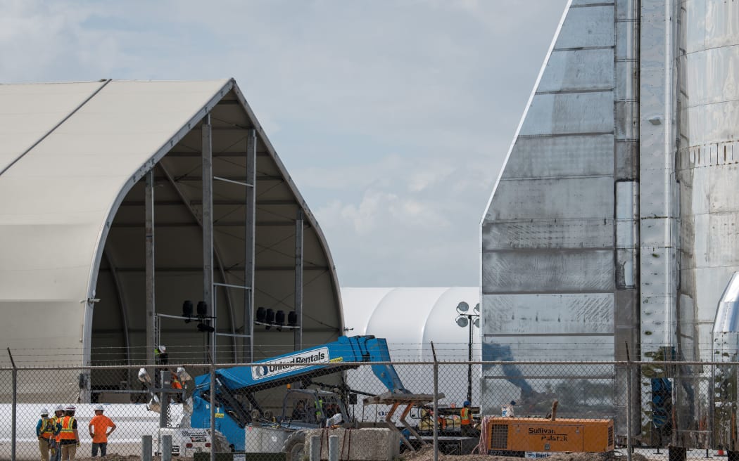 BOCA CHICA, TX - SEPTEMBER 28: Workers talk near the base of a prototype of SpaceX's Starship spacecraft at the company's Texas launch facility on September 28, 2019 in Boca Chica near Brownsville, Texas.
