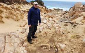 Dr Matthew Schmidt from the Department of Conservation next to in-situ deposit of moa bones on Rakiura.