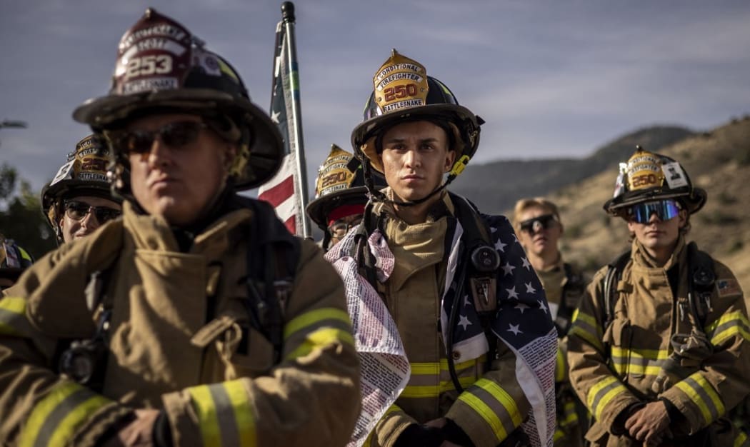 Firefighters in full gear pause for a moment of silence as they participate with first responders, victim's family members and supporters in Colorado