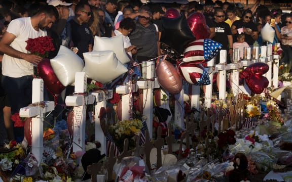 People pray and pay their respects at the makeshift memorial for victims of the shooting that left a total of 22 people dead in El Paso.
