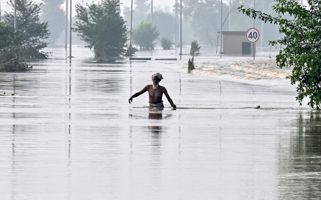 A man wades through a flooded area of Kartarpur, a town in Punjab province, on August 28, 2025. Pakistan authorities blew up an embankment next to a monsoon-engorged dam on August 27 as flooding submerged one of the world's holiest Sikh sites. Three transboundary rivers in the east of the country have swollen to exceptionally high levels as a result of heavy rains across the border in India. (Photo by Arif ALI / AFP)