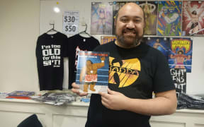 Michel Mulipola, a professional wrestler and comic book artist, stands with the book he illustrated at its launch.