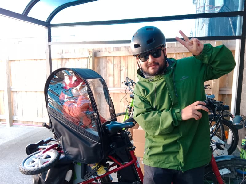Juan Parada rides in the rain with his five-year-old son.
