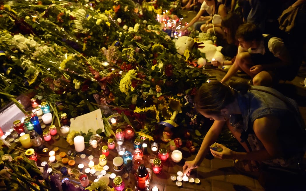 People light candles in front of the Embassy of the Netherlands in Kiev on July 17, 2014, to commemorate passengers of Malaysian Airlines flight MH17 carrying 295 people from Amsterdam to Kuala Lumpur which crashed in eastern Ukraine. Ukrainian President Petro Poroshenko said on July 17 that the Malaysia Airlines jet that crashed over rebel-held eastern Ukraine may have been shot down." Ukraine's government and pro-Russian insurgents traded blame for the disaster, with comments attributed to a rebel commander suggesting his men may have downed Malaysia Airlines flight MH17 by mistake, believing it was a Ukrainian army transport plane. AFP PHOTO/ SERGEI SUPINSKY (Photo by Sergei SUPINSKY / AFP)