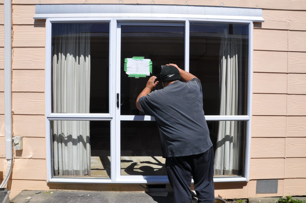 Pat Koti looks into his yellow-stickered rental home that was damaged during the floods in Westport.