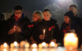 People lay flowers and lit candles in memory of the Moscow concert gun attack victims in the center of Simferopol, Crimea, on March 22, 2024. Gunmen opened fire at a Moscow concert hall on March 22, 2024 killing at least 40 people, wounding more than 100 and sparking an inferno, authorities said, with the Islamic State group claiming responsibility. (Photo by STRINGER / AFP)