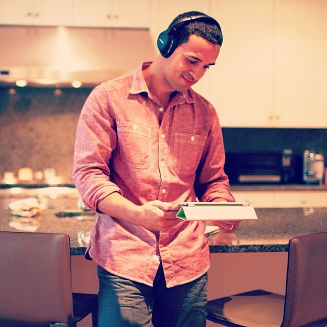 A man holding a tablet computer, wearing bluetooth headphones