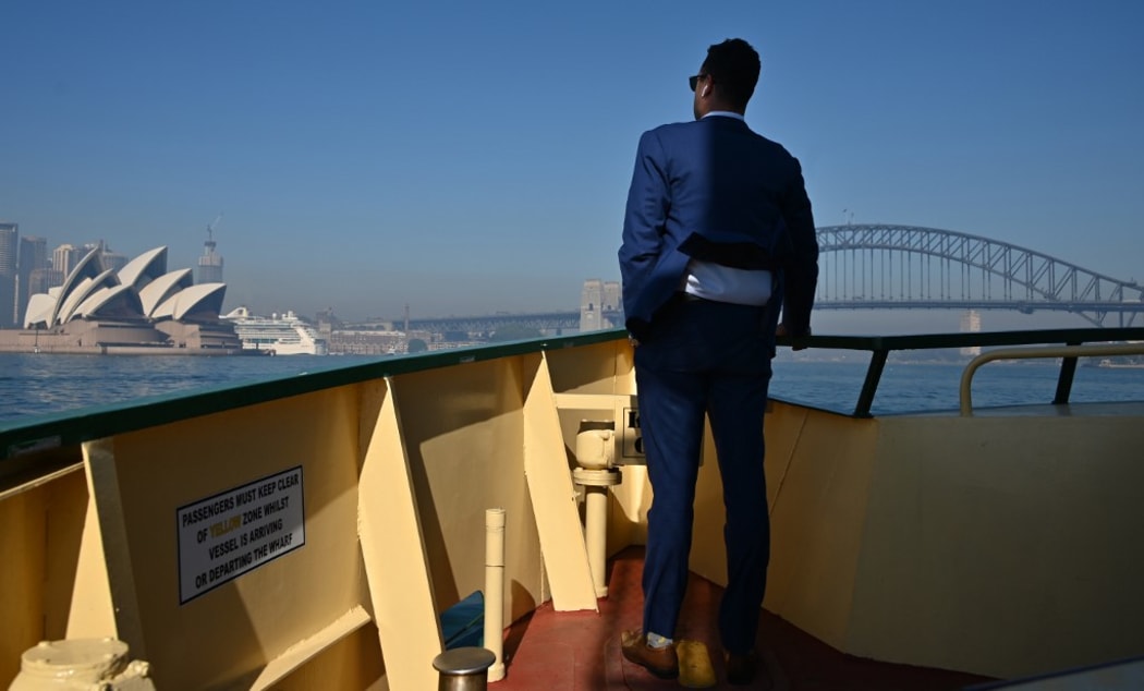 A commuter on a ferry watches as smoke from bushfires blankets Sydney on November 19, 2019. - Sydney woke up to a thick blanket of smoke as New South Wales warns residents of the dangers amid severe fire dangers and hot, windy weather. (Photo by PETER PARKS / AFP)