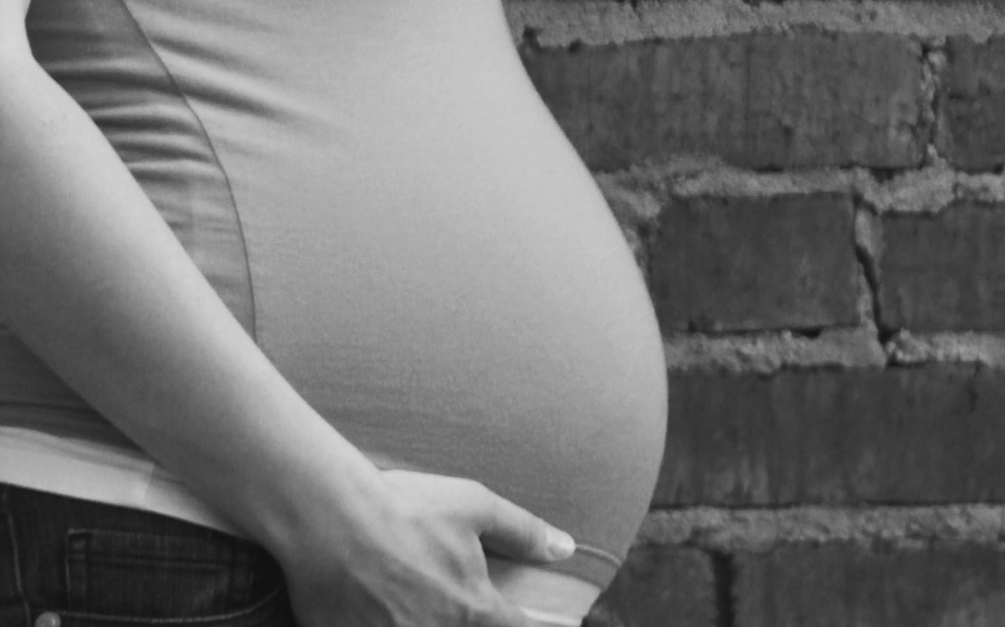 A young pregnant woman holds her belly