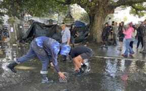 Protesters pull up pavers to throw at police outside Parliament.