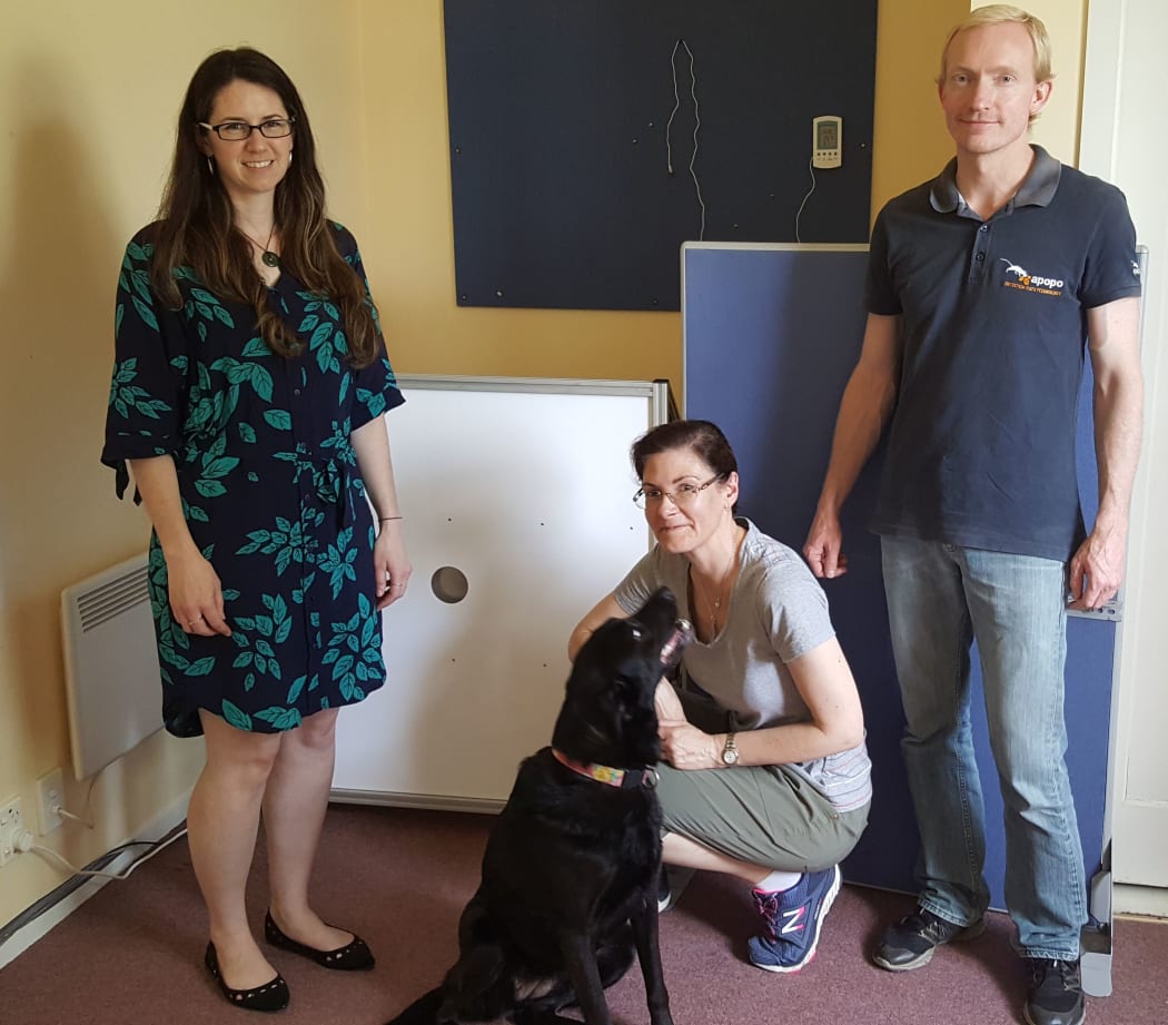 Clare Browne (left), Margaret Crawford with Ruby the black labrador and Tim Edwards standing in front of the experimental set-up - the round hole is the sniffing port for the dogs to put their noses in.
