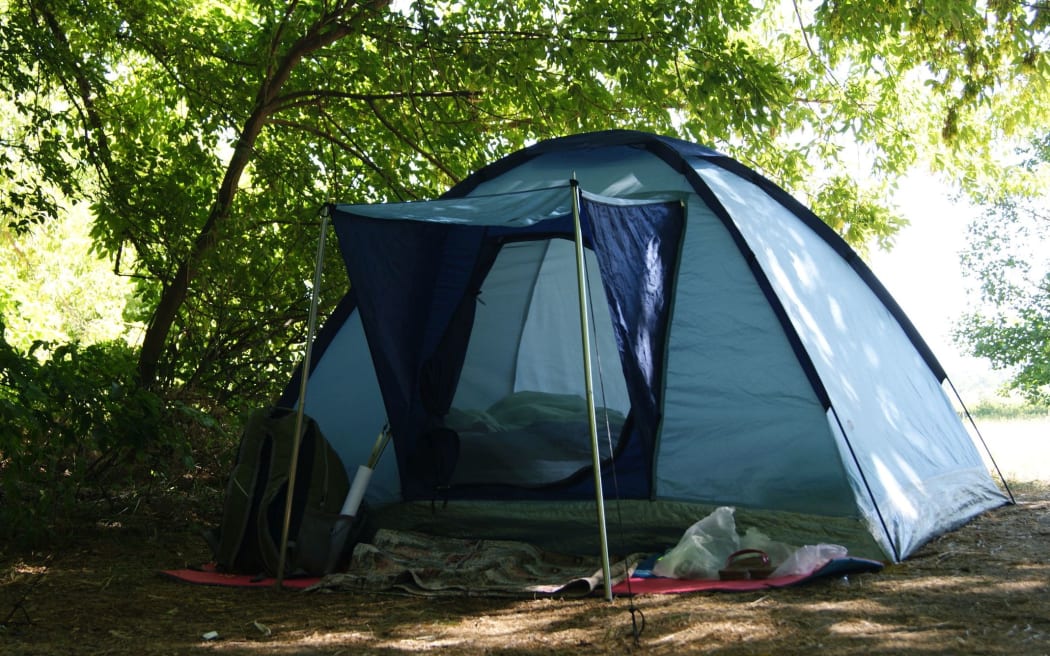 Small camping in a green forest. A blue tent. Travel concept, hiking, nature tour.