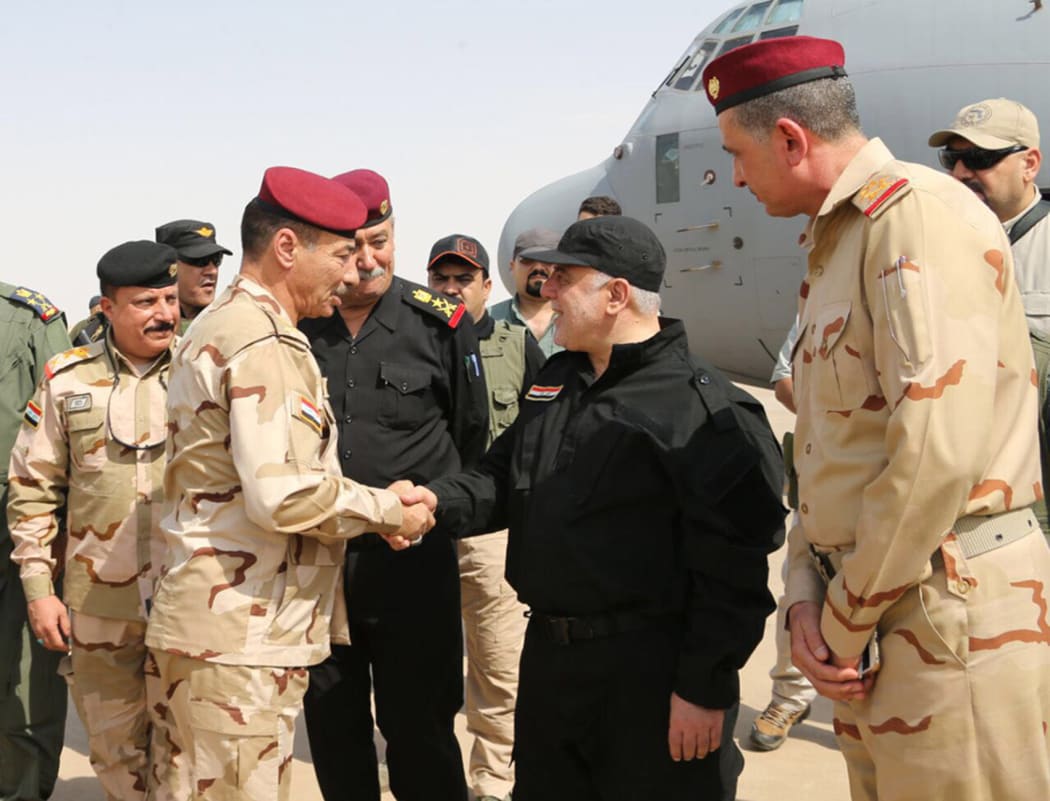Iraqi Prime Minister Haider al-Abadi (C-R) shaking hands with army officers upon his arrival in Mosul