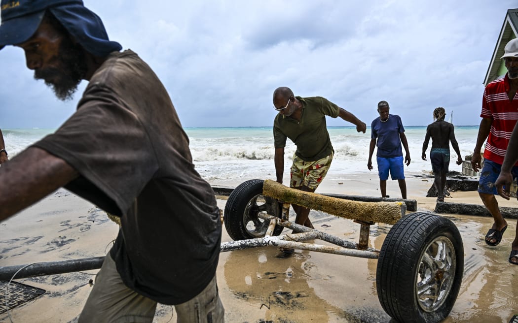 Residents clear boat from the street as it gets flooded after the hurricane Beryl passes in the parish of Saint James, Barbados, near to Bridgetown, Barbados on July 1, 2024. Hurricane Beryl plowed toward the southeast Caribbean early Monday as officials warned residents to seek shelter ahead of powerful winds and swells expected from the Category 3 storm. (Photo by CHANDAN KHANNA / AFP)