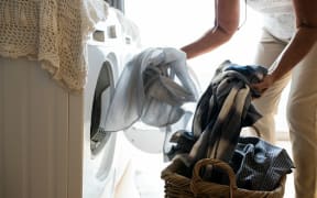 A person putting laundry in a washing machine