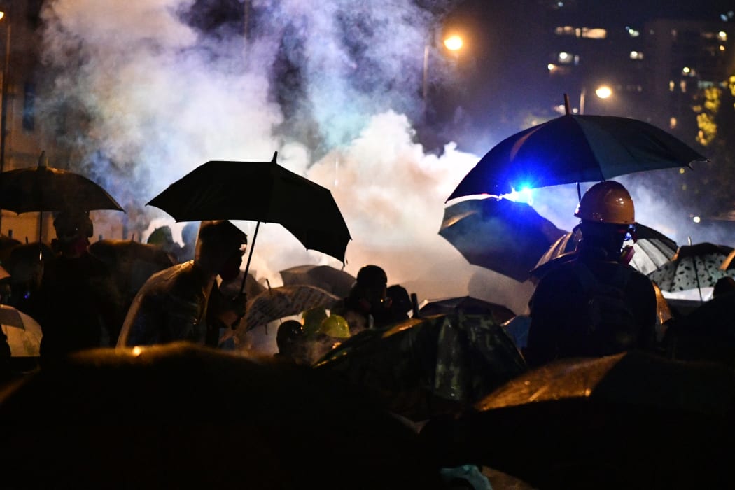 Anti-government protesters run as tear gas is being fired by the police outside the Polytechnic University of Hong Kong in Hung Hom district of Hong Kong, early on November 18, 2019.