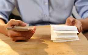 Closeup of person calculating or paying bills. Woman using smartphone. Online payment concept. Cropped view.